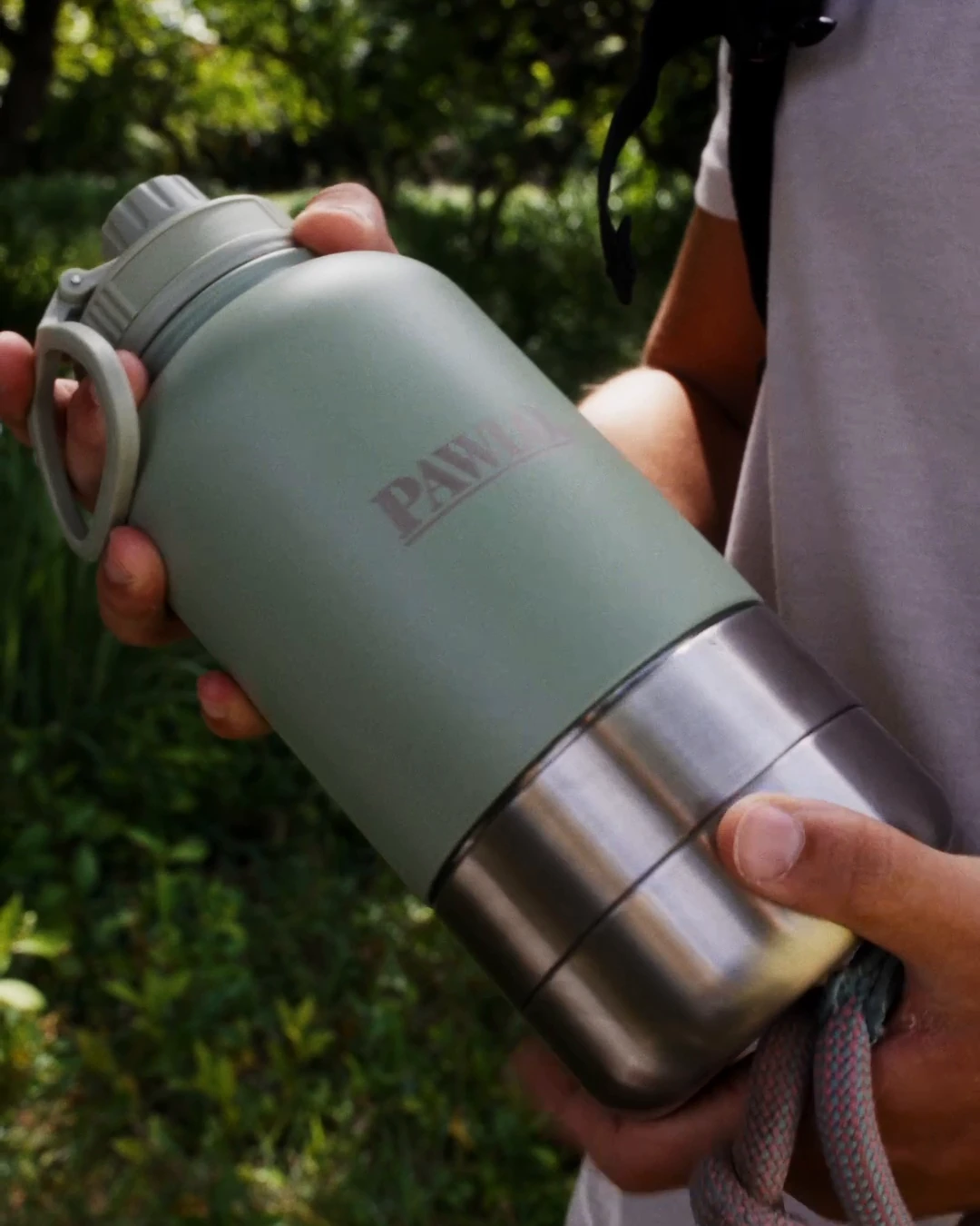 The real Sage PAWLO bottle held in one hand, showing its size. A frame from owner-supplied outdoor footage.